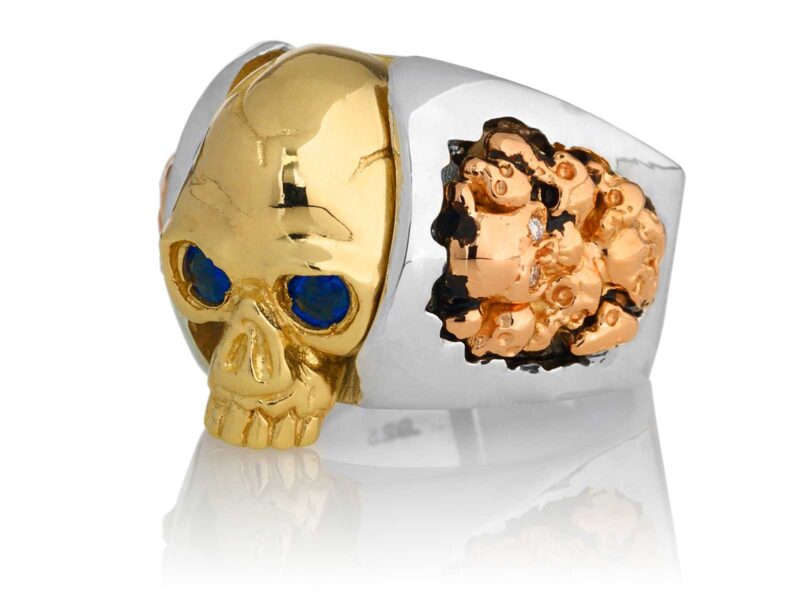 RG1030YGSIL-B Judge and Jury Skull Ring (Front Left Side View) in Yellow Gold and Sterling Silver with Blue Sapphires and White Diamonds, designed by Steve Soffa